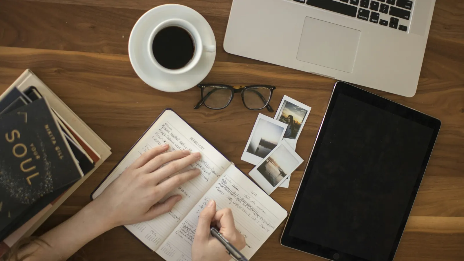 Person drafting company profile content by hand in a notebook beside a laptop
