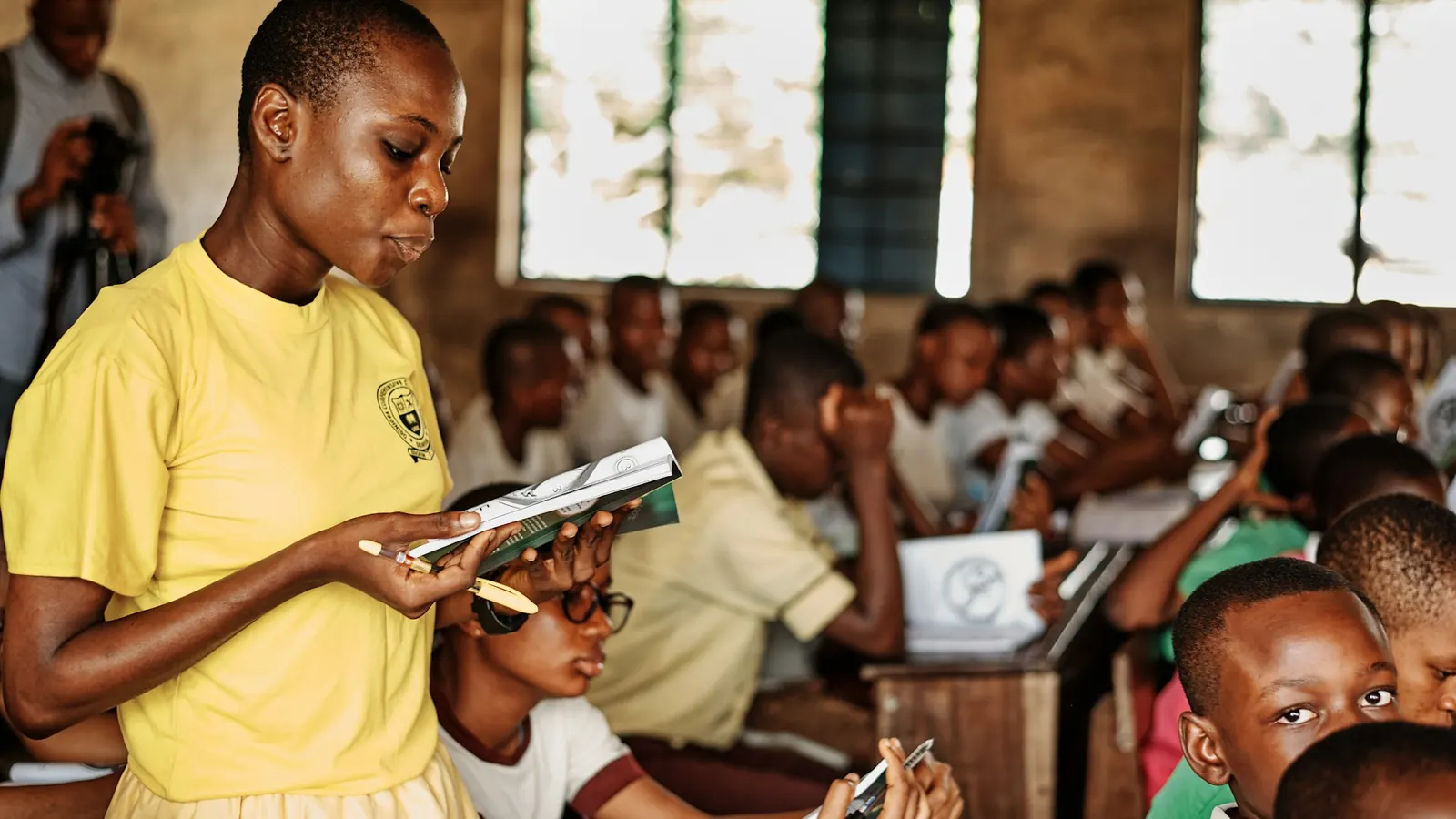 Teacher reading with pupils in a busy African school classroom