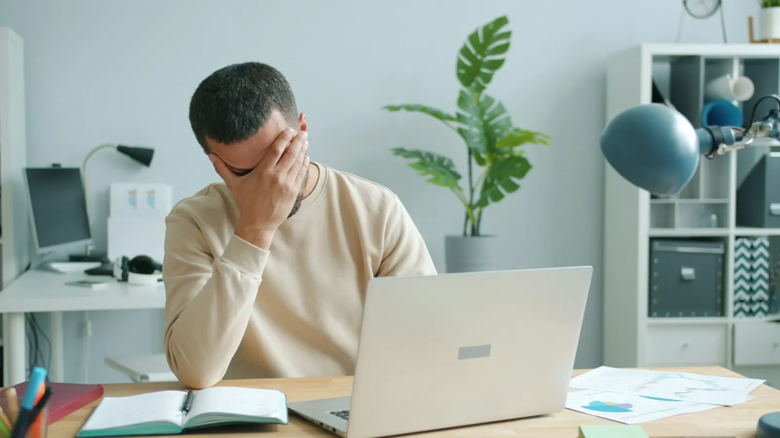 Frustrated business owner holding his head in front of a laptop