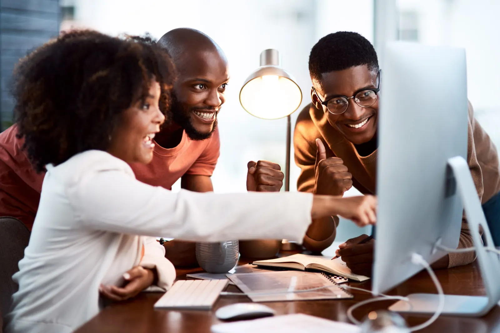 Bravura team celebrating as they review a client's new website on a desktop screen